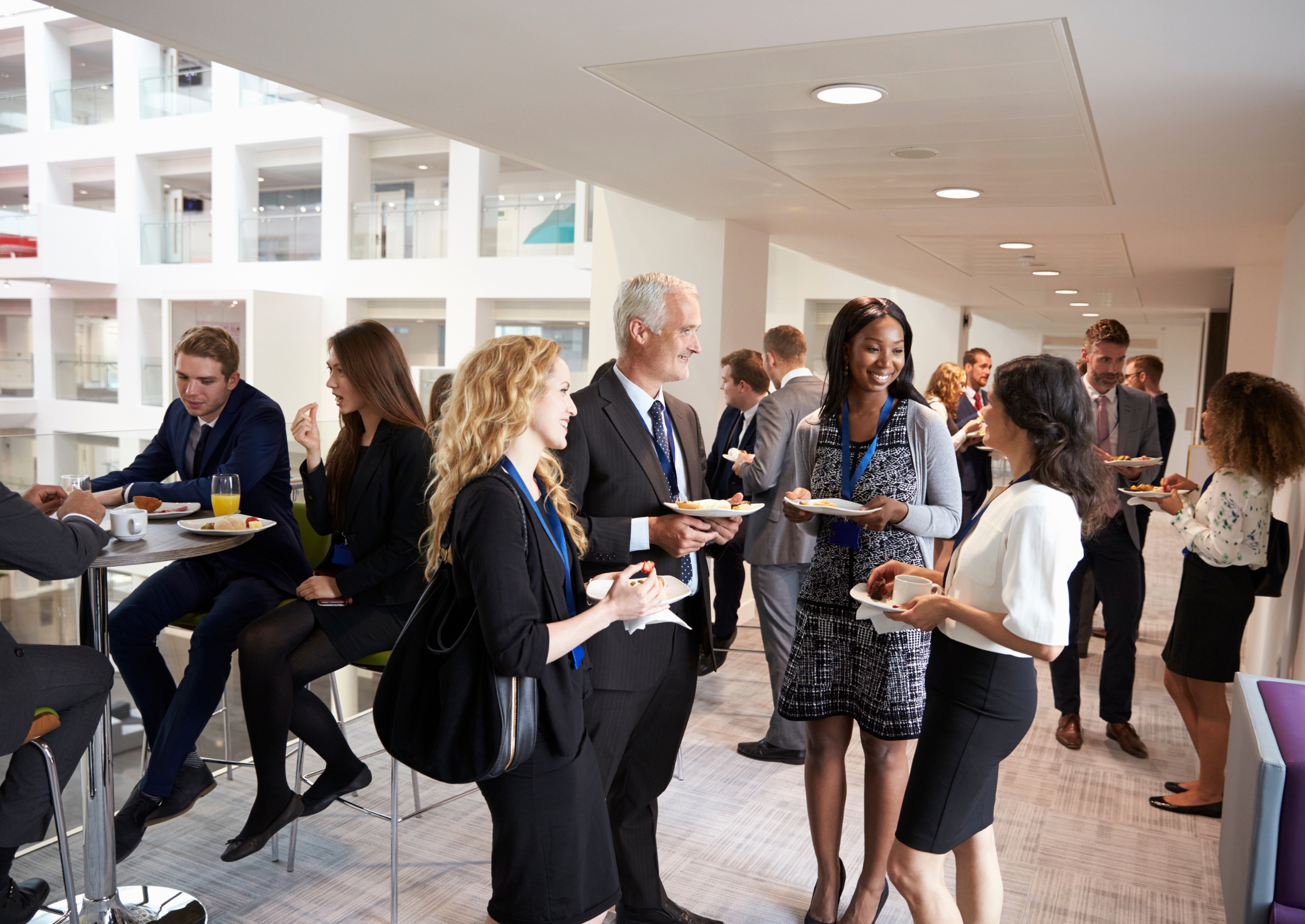 Berufstätige Frauen und Männer unterhalten sich und essen gemeinsam während einer Kaffeepause auf einer Geschäftsveranstaltung oder Konferenz.